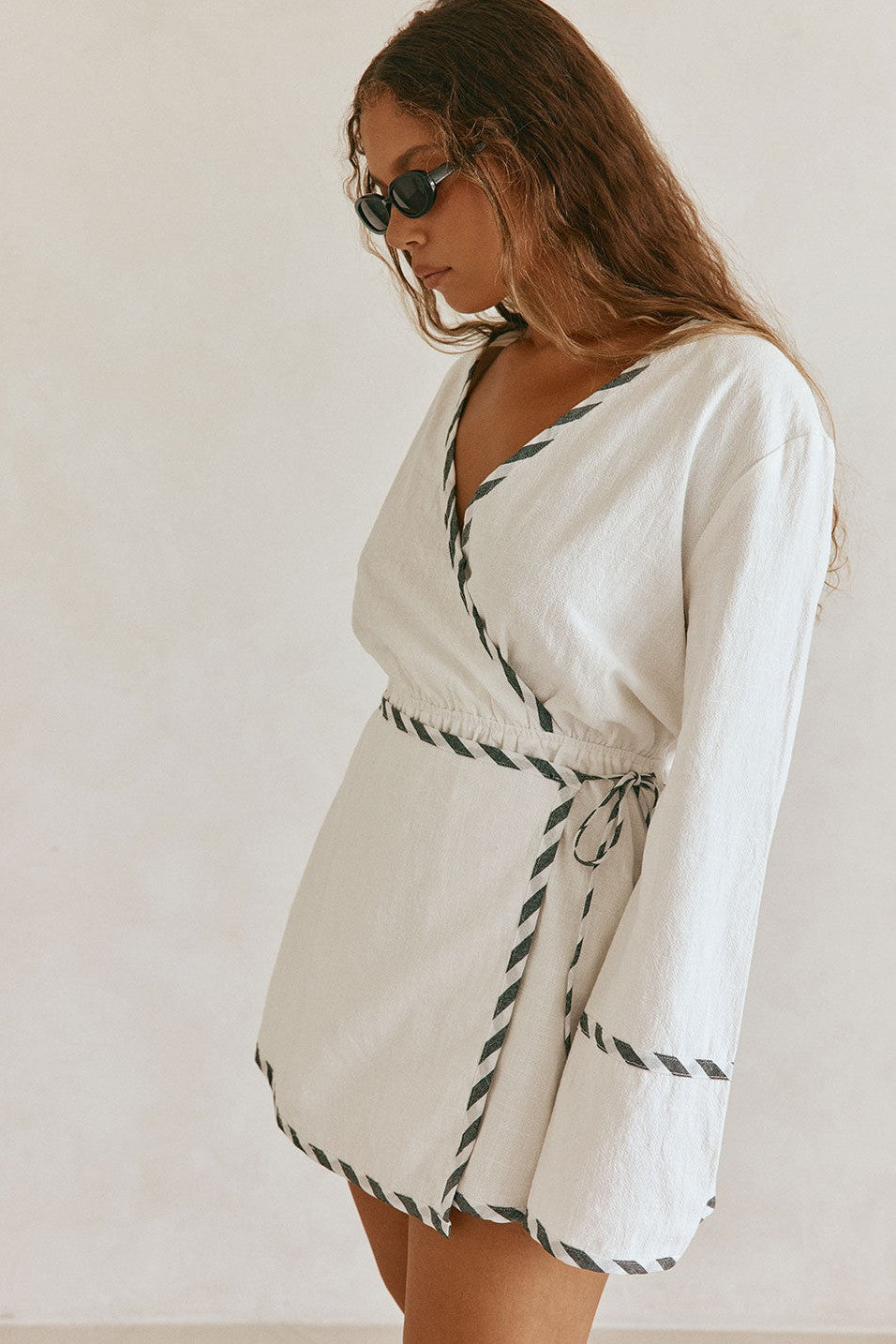White mini dress with a wrap silhouette, styled on model