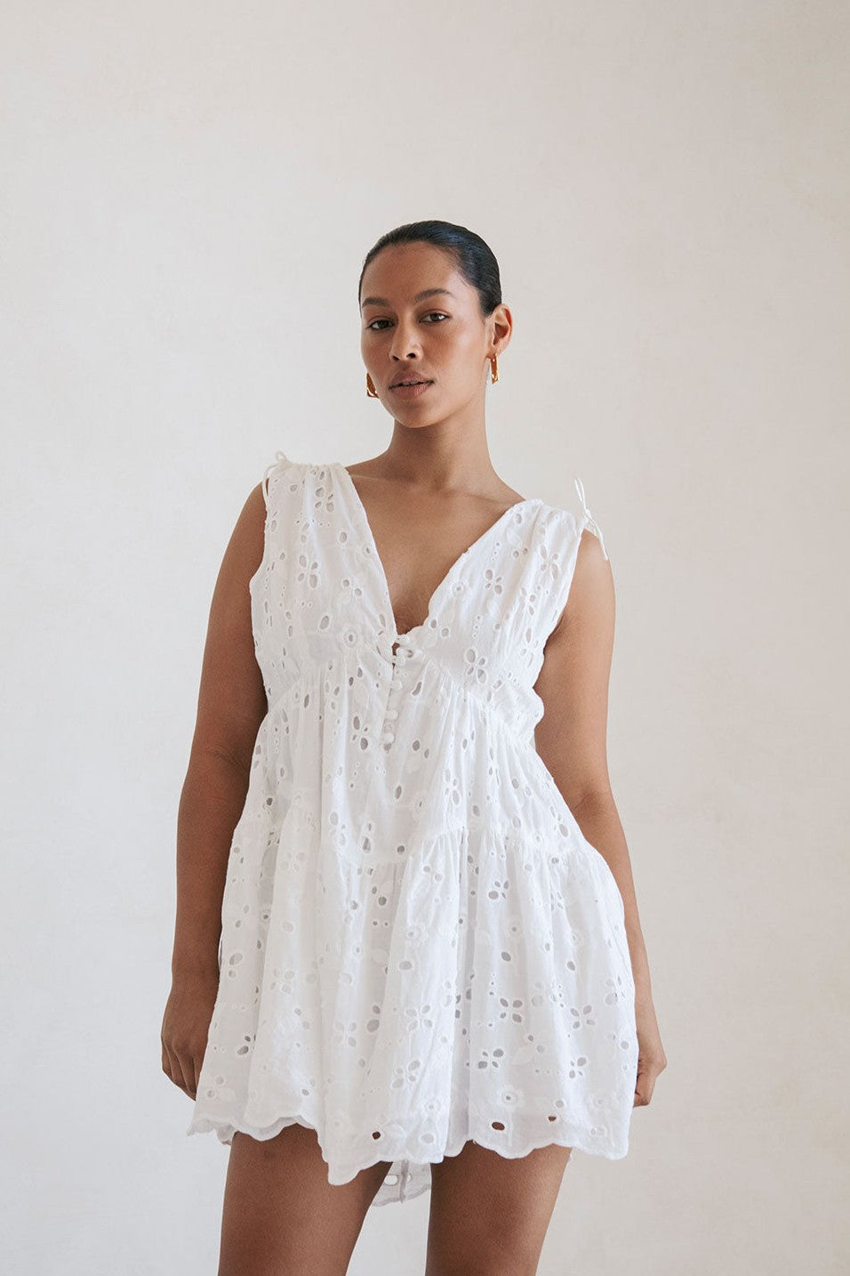 White mini dress with a V neckline, styled on model