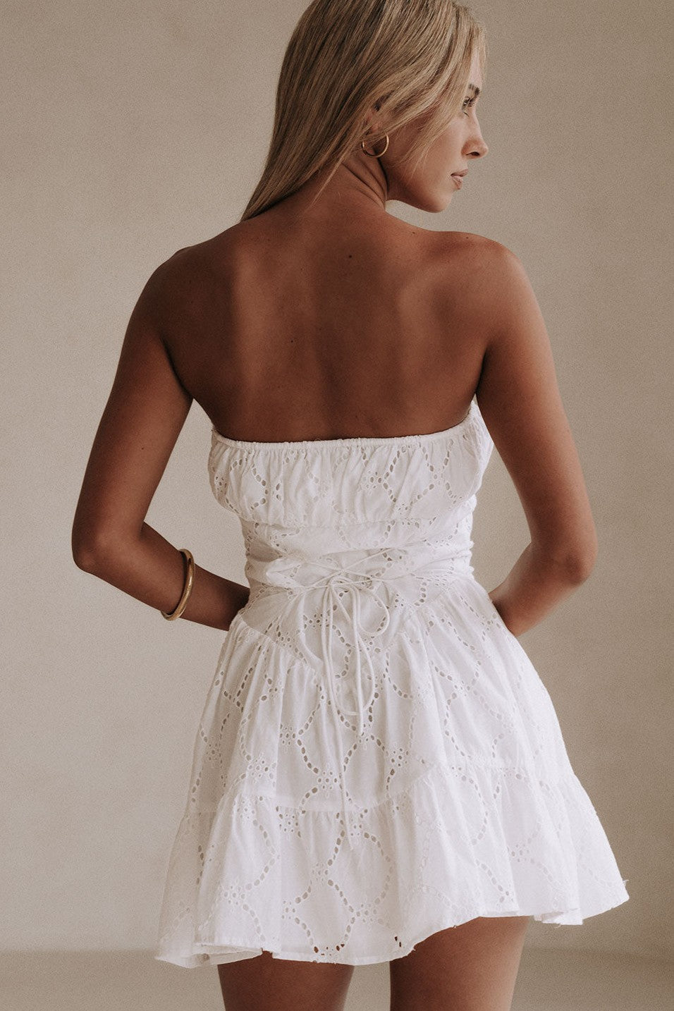 White mini dress with a strapless neckline, styled on model