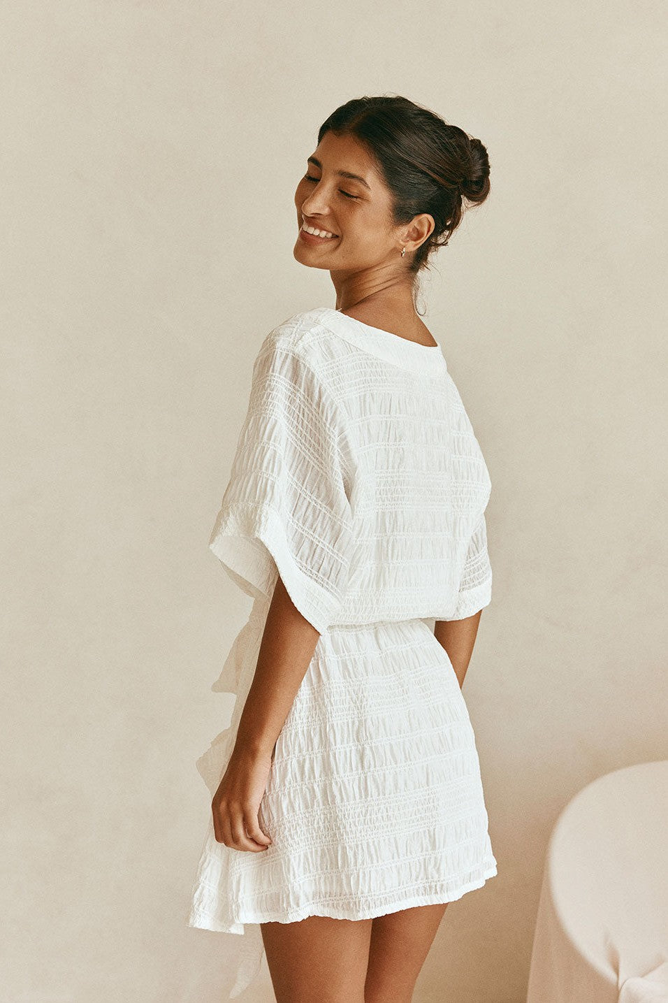 White mini dress with a V neckline, styled on model